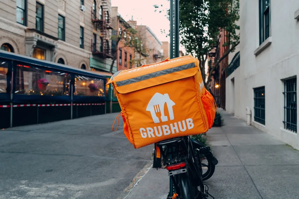 Orange GrubHub delivery box on the back of a bicycle.